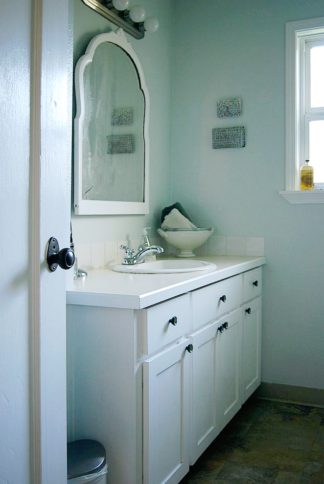 Small beach style bathroom in Portland with shaker cabinets, white cabinets, laminate benchtops, white tile, ceramic tile, blue walls and linoleum floors.
