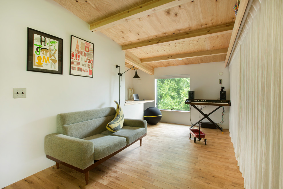 Mittelgroßes Modernes Arbeitszimmer mit Arbeitsplatz, weißer Wandfarbe, braunem Holzboden, Einbau-Schreibtisch, freigelegten Dachbalken und Holzdielenwänden in Sonstige