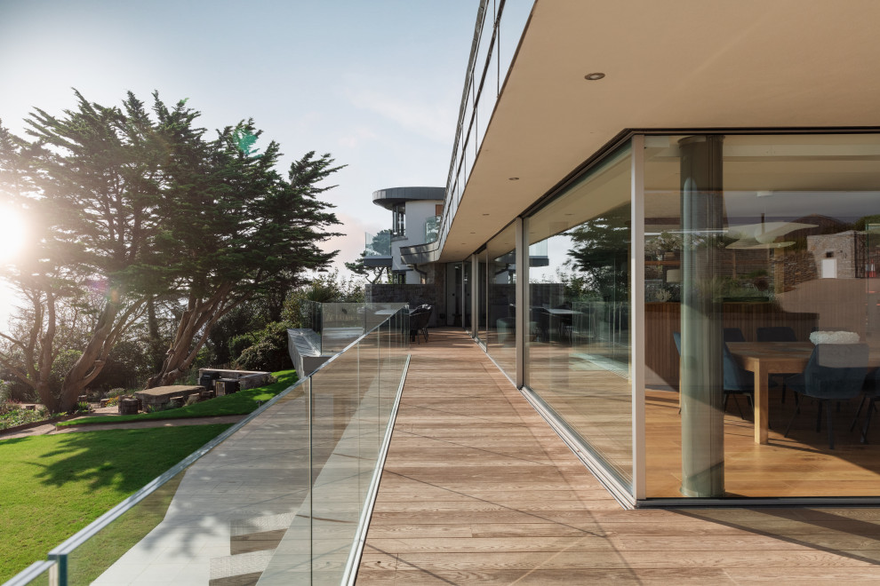 Inspiration for a large coastal glass railing balcony in Cornwall with a roof extension.