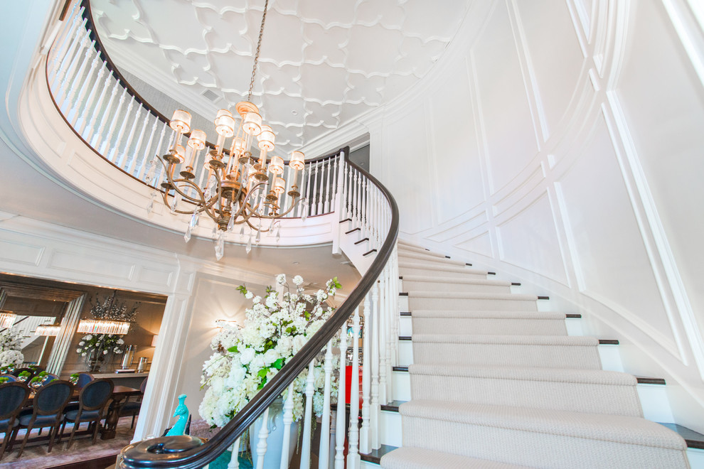 Photo of a large traditional carpeted curved staircase in New York with wood risers and wood railing.