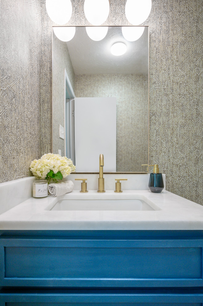 Photo of a small classic cloakroom in Dallas with shaker cabinets, blue cabinets, a two-piece toilet, multi-coloured walls, porcelain flooring, a submerged sink, marble worktops, beige floors, white worktops, a built in vanity unit and wallpapered walls.