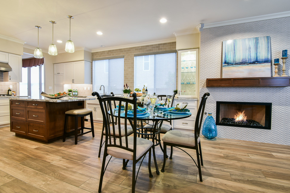 This is an example of a mid-sized beach style u-shaped open plan kitchen in San Diego with a farmhouse sink, shaker cabinets, white cabinets, quartz benchtops, grey splashback, ceramic splashback, stainless steel appliances, ceramic floors and with island.