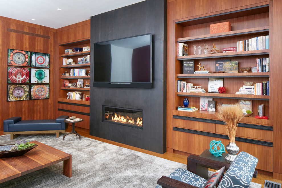 This is an example of a large contemporary formal enclosed living room in New York with brown walls, medium hardwood floors, a ribbon fireplace, a metal fireplace surround, a wall-mounted tv and brown floor.
