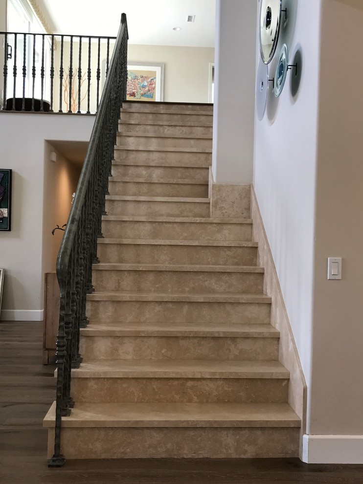 Photo of a mid-sized transitional travertine straight staircase in Orange County with travertine risers and metal railing.