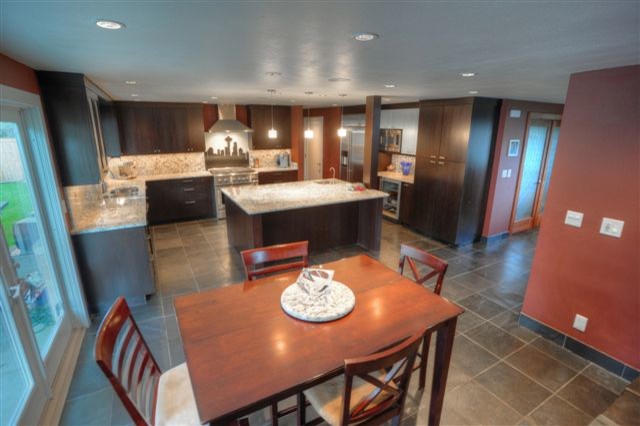 Photo of a large traditional open plan kitchen in Seattle with dark wood cabinets, granite benchtops, stainless steel appliances, terra-cotta floors and with island.