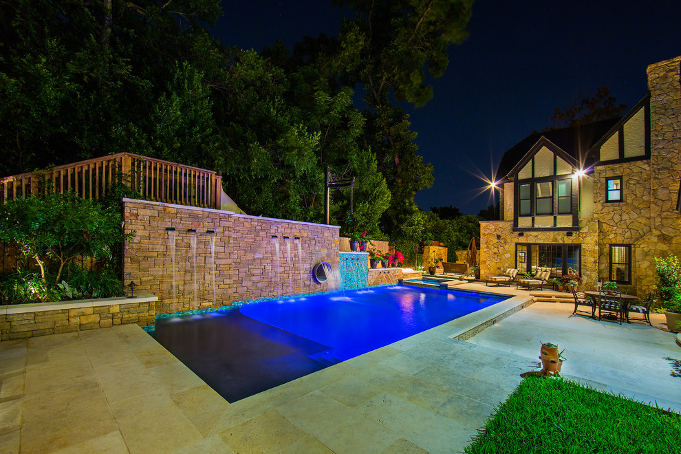 Large country side yard rectangular lap pool in Austin with a water slide and natural stone pavers.