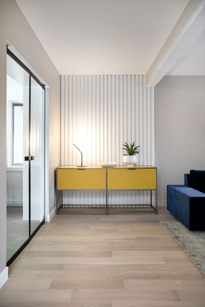 Cette image montre un salon minimaliste de taille moyenne et ouvert avec une salle de réception, un mur blanc, parquet clair et du lambris.