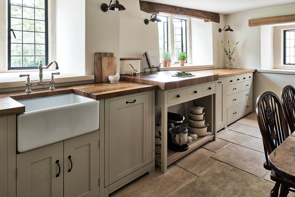 Photo of a large country l-shaped eat-in kitchen in Wiltshire with a farmhouse sink, shaker cabinets, wood benchtops, beige splashback, ceramic splashback, limestone floors and no island.