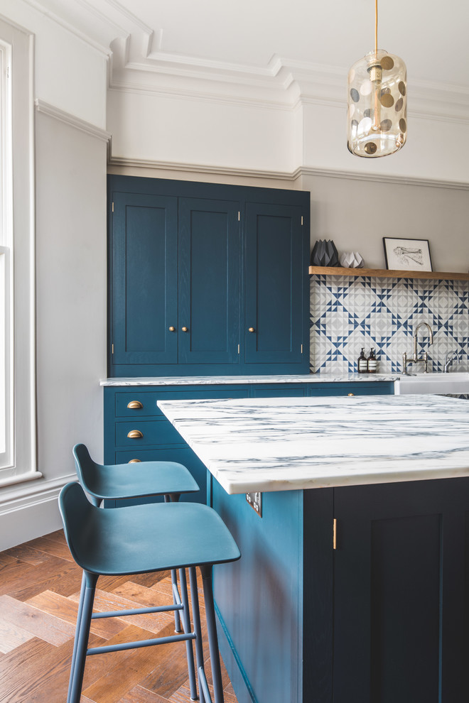 Inspiration for a large contemporary l-shaped eat-in kitchen in Other with a farmhouse sink, shaker cabinets, blue cabinets, marble benchtops, blue splashback, cement tile splashback, stainless steel appliances, dark hardwood floors, with island and brown floor.