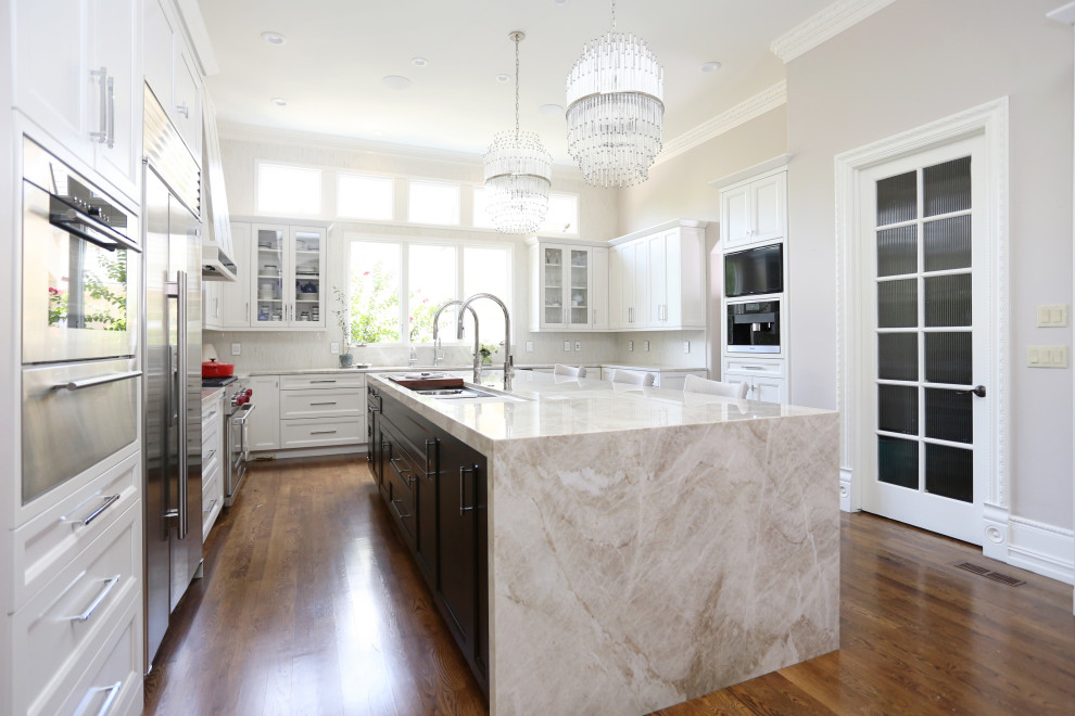 Inspiration for a huge transitional medium tone wood floor and brown floor open concept kitchen remodel with an undermount sink, recessed-panel cabinets, white cabinets, quartzite countertops, white backsplash, ceramic backsplash, stainless steel appliances, an island and white countertops