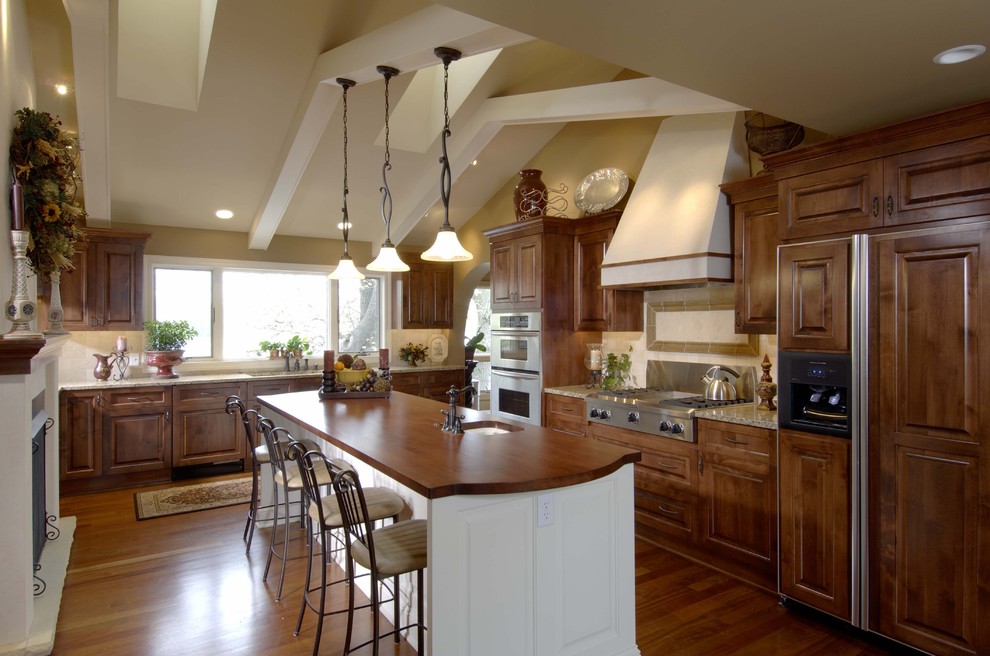 Inspiration for a traditional kitchen in Minneapolis with raised-panel cabinets, wood benchtops, dark wood cabinets and panelled appliances.