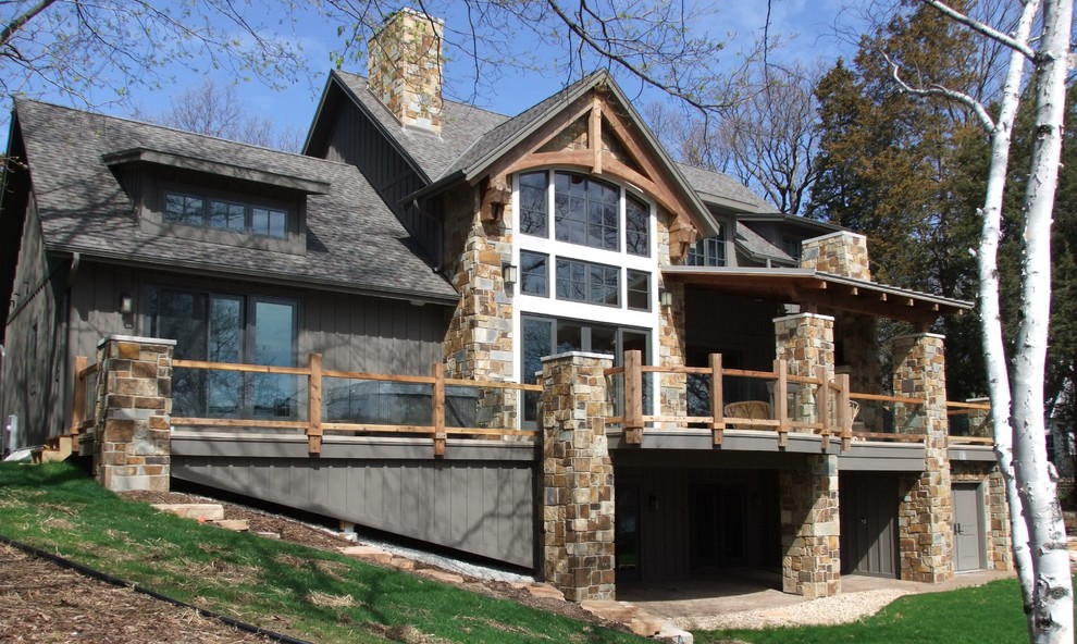 Mid-sized traditional two-storey grey house exterior in Milwaukee with stone veneer, a hip roof and a tile roof.
