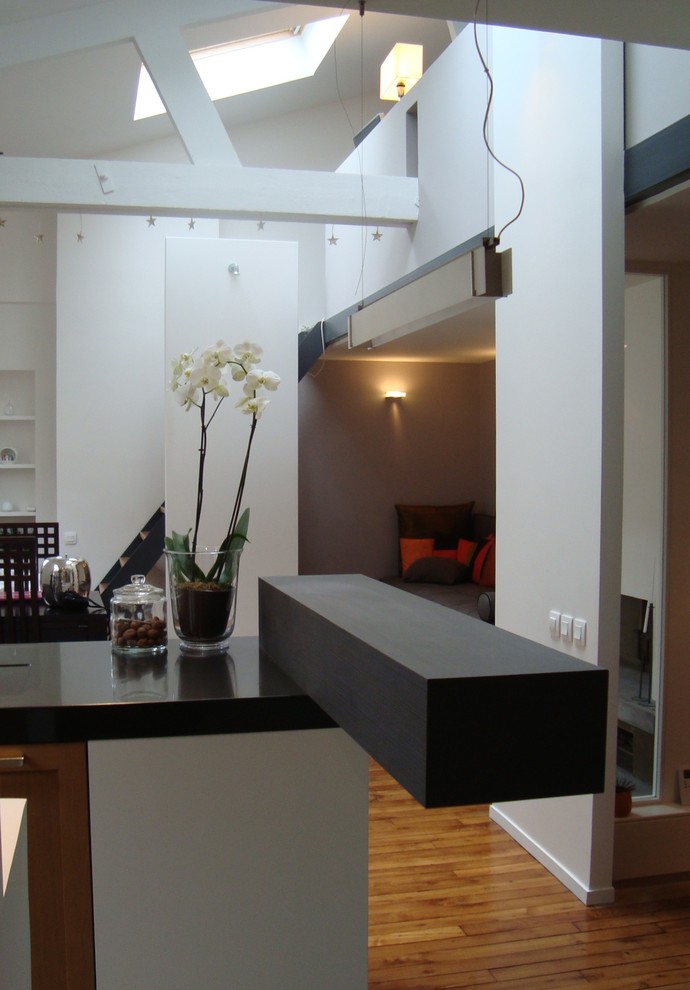 Inspiration pour salon in U and bois clair With un évier intégré, un placard avec porte à panneau encastré, un plan de travail en surface solide, une crédence blanche, un électroménager en acier inoxydable, îlot, un mur blanc, un sol en bois brun, une cheminée d'angle, un manteau de cheminée en plâtre, aucun téléviseur and un sol beige.