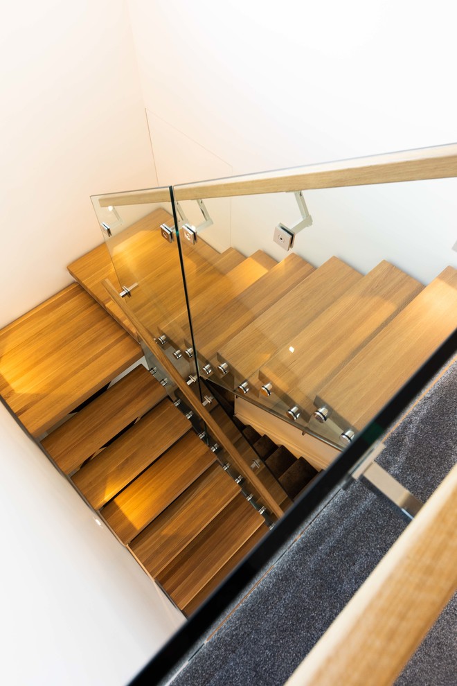 Inspiration for a large contemporary wood floating staircase in Auckland with open risers and glass railing.