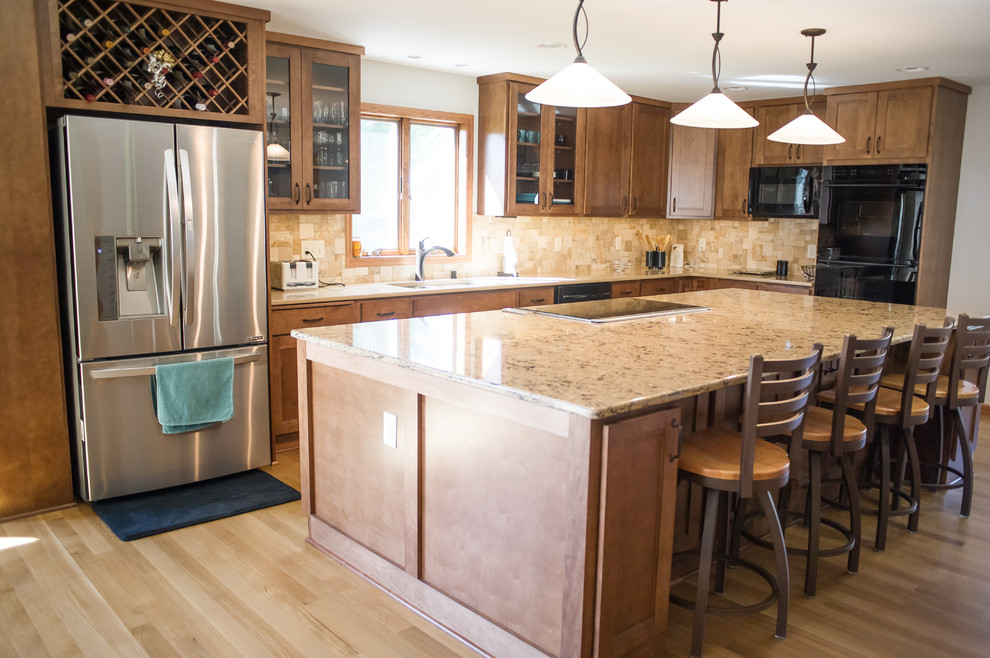 Example of a large transitional l-shaped dark wood floor open concept kitchen design with an undermount sink, recessed-panel cabinets, medium tone wood cabinets, quartz countertops, beige backsplash, black appliances and an island