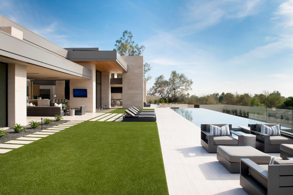 This is an example of a large contemporary backyard rectangular infinity pool in Phoenix.