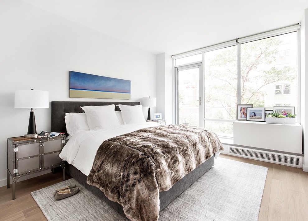 This is an example of a mid-sized contemporary master bedroom in New York with white walls and light hardwood floors.