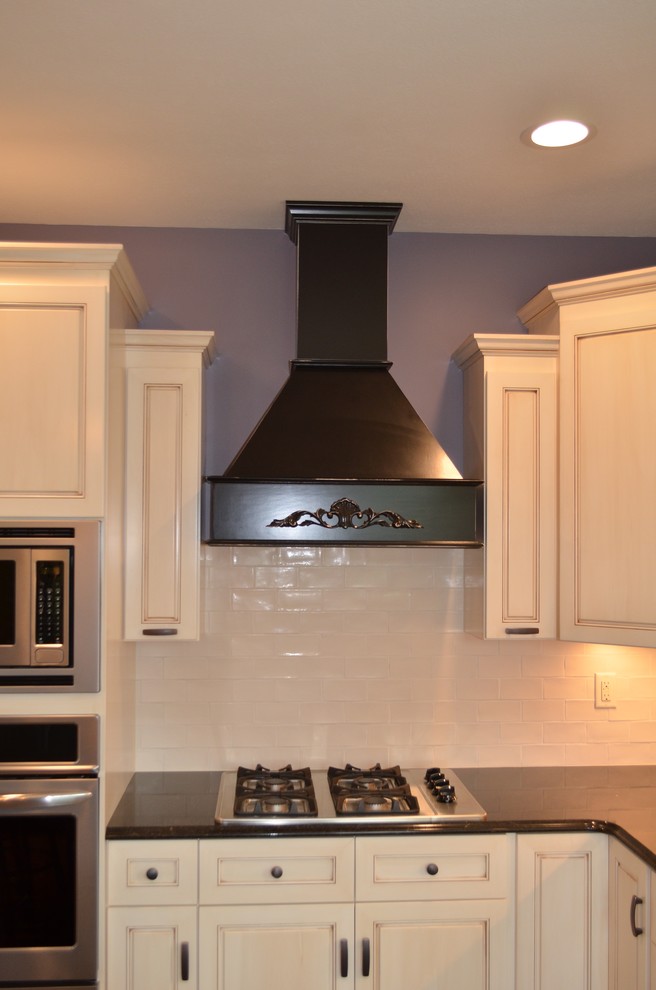 Example of a mid-sized transitional u-shaped brown floor eat-in kitchen design with a double-bowl sink, recessed-panel cabinets, light wood cabinets, solid surface countertops, white backsplash, stone tile backsplash, stainless steel appliances and an island