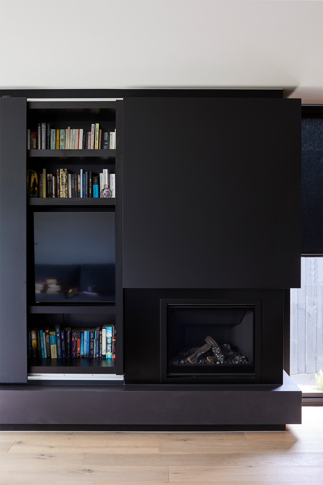 This is an example of a small modern study in Melbourne with light hardwood flooring, a standard fireplace, a metal fireplace surround and a built-in desk.