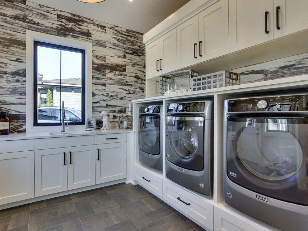 This is an example of a large country l-shaped dedicated laundry room in Portland with an undermount sink, shaker cabinets, white cabinets, quartz benchtops, multi-coloured walls, ceramic floors, a side-by-side washer and dryer and brown floor.