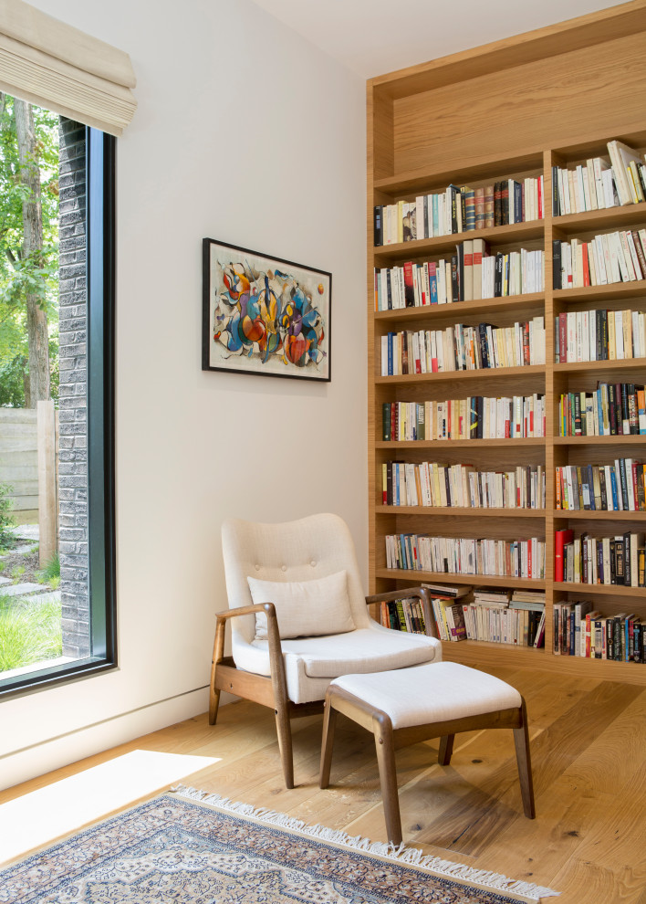 Cette photo montre un bureau moderne de taille moyenne avec une bibliothèque ou un coin lecture, un mur blanc, parquet clair, aucune cheminée, un bureau intégré et un sol beige.