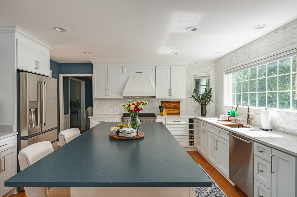 Modern inredning av ett mellanstort grå grått kök, med en undermonterad diskho, skåp i shakerstil, vita skåp, bänkskiva i kvarts, vitt stänkskydd, stänkskydd i marmor, rostfria vitvaror, ljust trägolv, en köksö och brunt golv