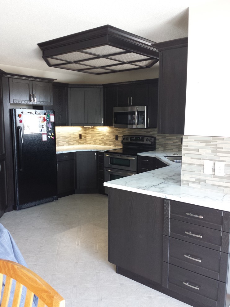 Photo of a mid-sized transitional u-shaped separate kitchen in Calgary with an undermount sink, shaker cabinets, black cabinets, marble benchtops, beige splashback, matchstick tile splashback, stainless steel appliances, ceramic floors, no island and beige floor.
