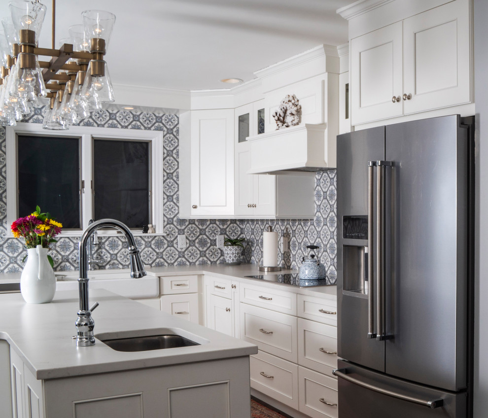 Inspiration for a mid-sized transitional l-shaped medium tone wood floor and brown floor eat-in kitchen remodel in St Louis with a farmhouse sink, recessed-panel cabinets, white cabinets, quartz countertops, blue backsplash, ceramic backsplash, stainless steel appliances, an island and white countertops