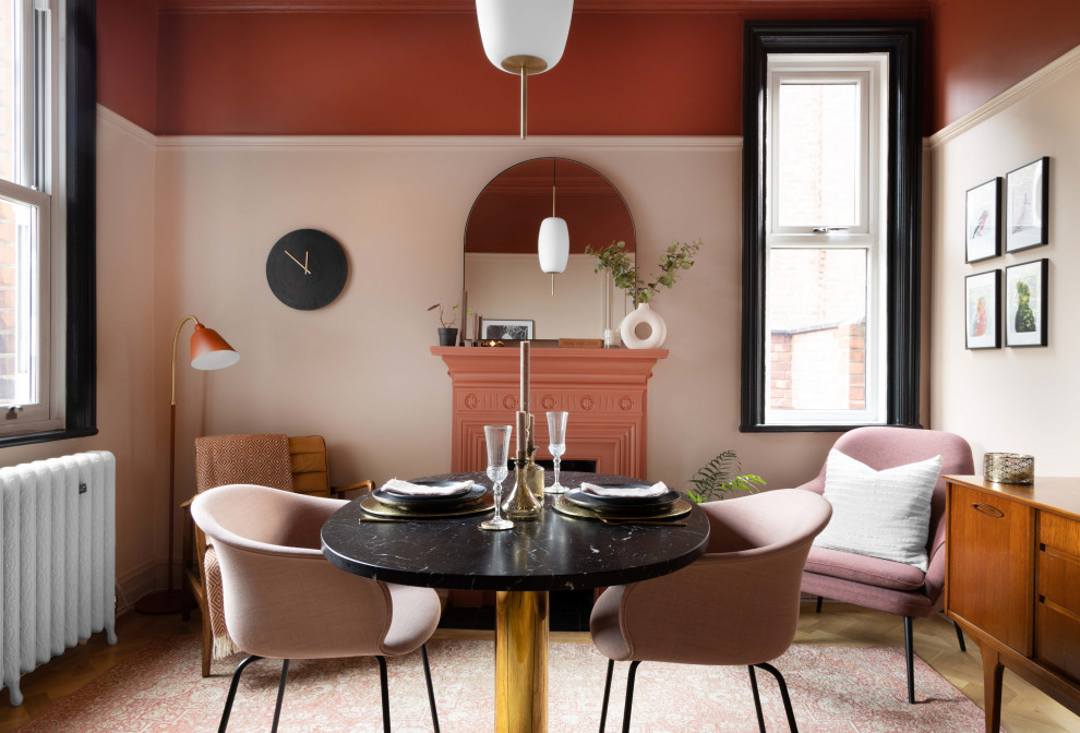 Ejemplo de comedor de cocina retro pequeño con paredes rosas, suelo de madera clara, todas las chimeneas y marco de chimenea de metal