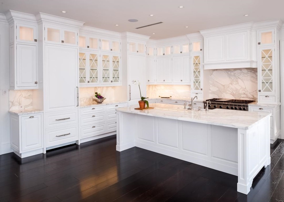 Large transitional l-shaped eat-in kitchen in Toronto with a farmhouse sink, raised-panel cabinets, white cabinets, marble benchtops, multi-coloured splashback, marble splashback, stainless steel appliances, vinyl floors, with island and black floor.