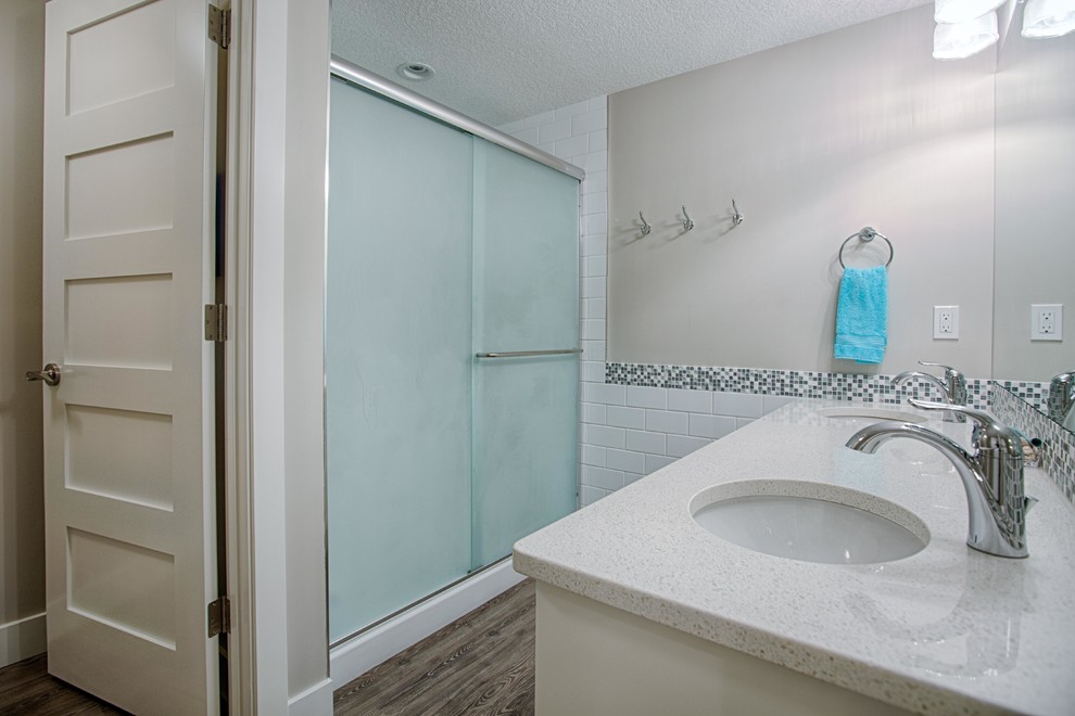 Alcove shower - mid-sized transitional 3/4 white tile and subway tile dark wood floor alcove shower idea in Calgary with white cabinets, white walls, an undermount sink and quartz countertops