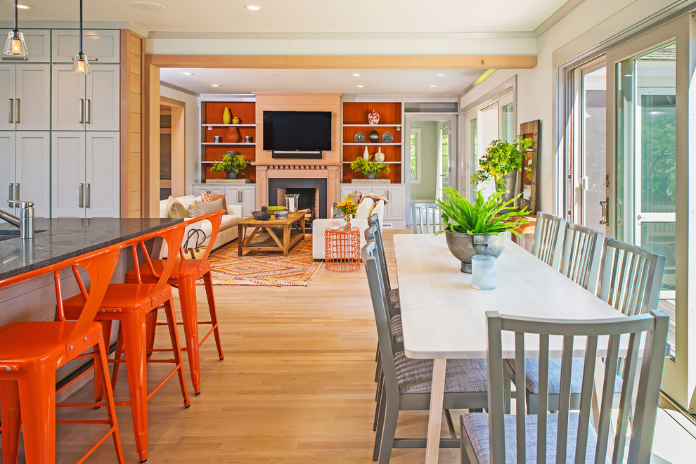 This is an example of a mid-sized eclectic open plan dining in Boston with white walls, light hardwood floors, a standard fireplace and a stone fireplace surround.