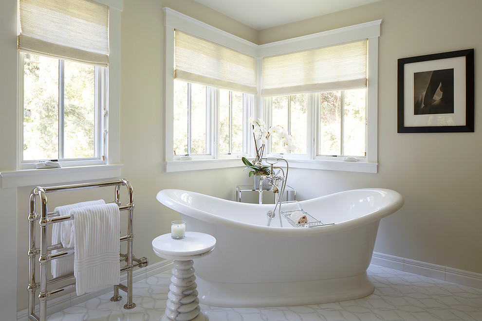 Inspiration for a large transitional master bathroom in San Francisco with a drop-in sink, recessed-panel cabinets, medium wood cabinets, marble benchtops, a freestanding tub, white tile, beige walls, marble floors and white floor.