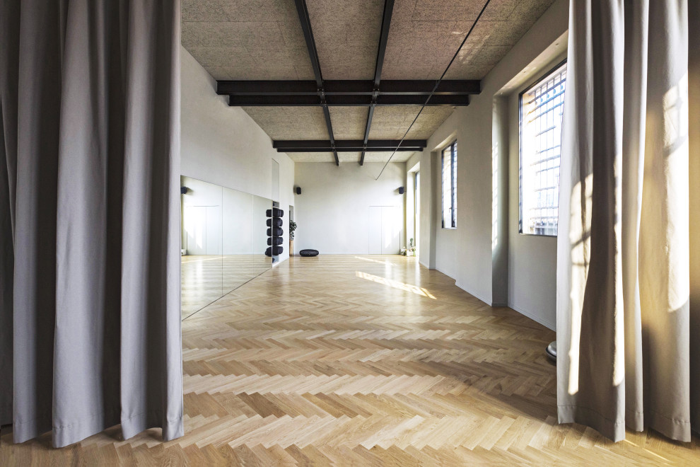 This is an example of a large scandinavian home yoga studio in Milan with white walls, light hardwood floors and beige floor.
