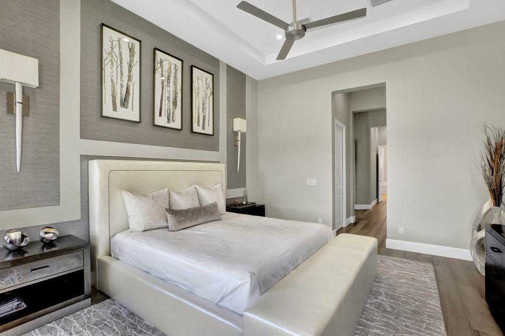 Large contemporary master bedroom in Miami with grey walls, light hardwood floors and grey floor.