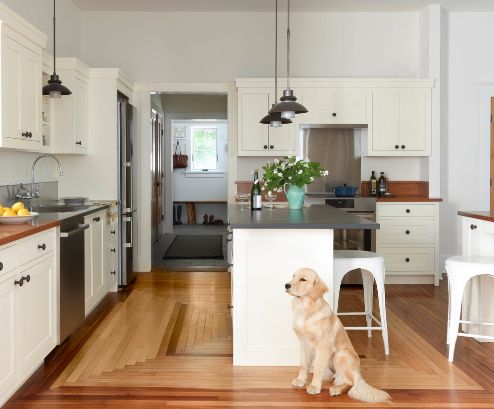 Design ideas for a transitional kitchen in Burlington with an integrated sink, shaker cabinets, beige cabinets, metallic splashback, medium hardwood floors, with island, brown floor and black benchtop.