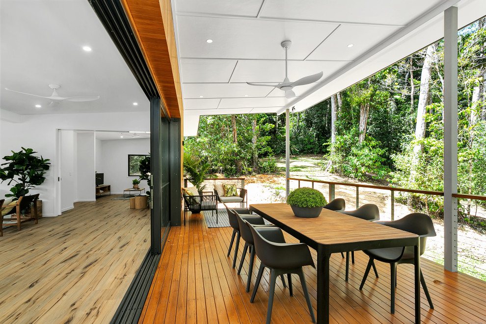 This is an example of a contemporary deck in Cairns with a roof extension and cable railing.