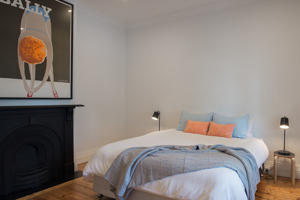 This is an example of a mid-sized contemporary guest bedroom in Melbourne with white walls, light hardwood floors, a standard fireplace and a metal fireplace surround.