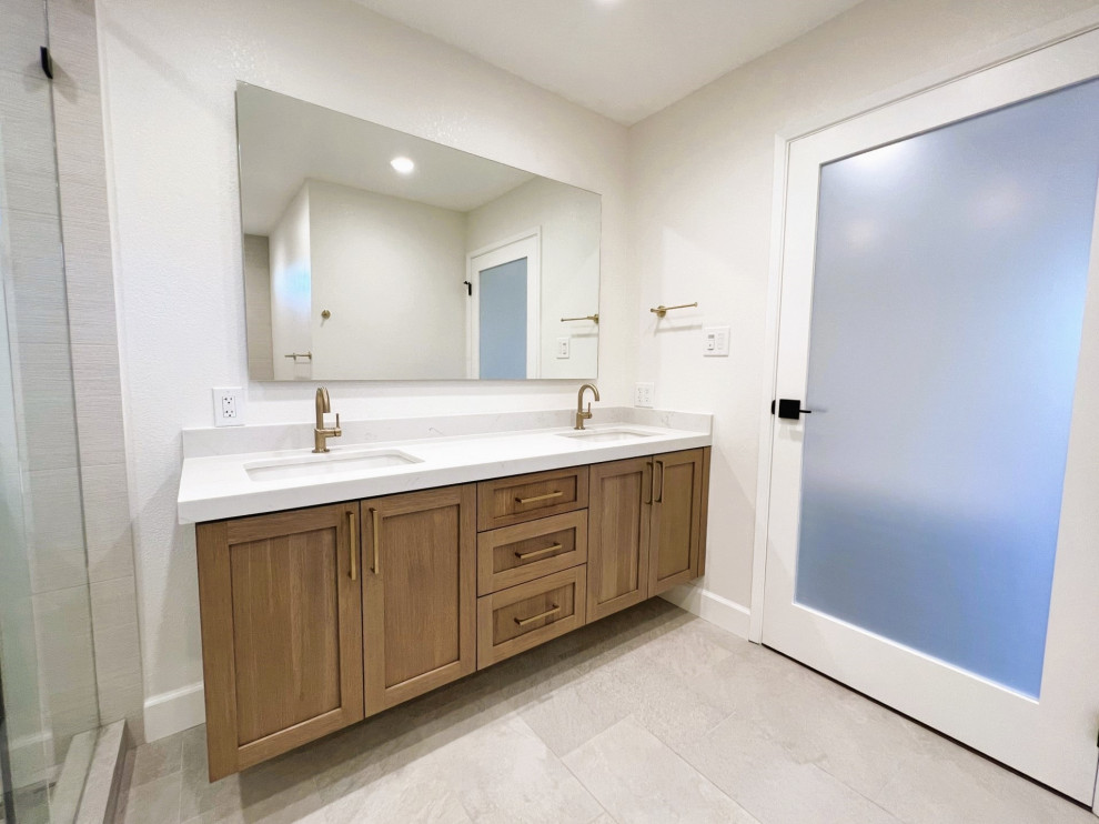 Idée de décoration pour une grande salle de bain principale vintage avec un placard à porte shaker, des portes de placard marrons, une baignoire indépendante, une douche d'angle, WC à poser, un carrelage beige, des carreaux de porcelaine, un mur blanc, un sol en carrelage de porcelaine, un lavabo encastré, un plan de toilette en quartz modifié, un sol beige, une cabine de douche à porte coulissante, un plan de toilette blanc, une niche, meuble double vasque et meuble-lavabo suspendu.