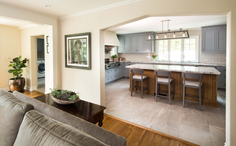 Large transitional u-shaped porcelain tile and gray floor enclosed kitchen photo in Los Angeles with a drop-in sink, shaker cabinets, quartzite countertops, white backsplash, ceramic backsplash, stainless steel appliances, an island and gray countertops