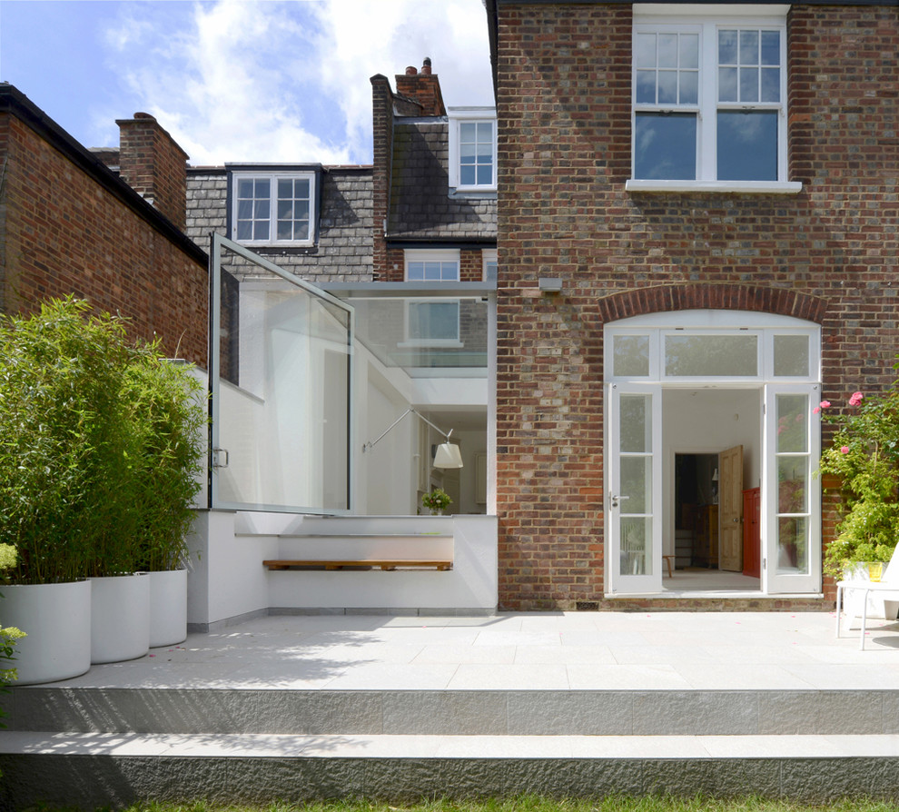This is an example of a mid-sized contemporary stucco exterior in London with a flat roof.