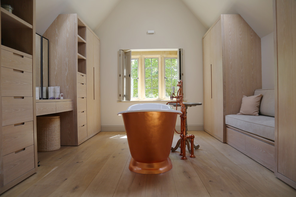 This is an example of a mid-sized contemporary master bathroom in Gloucestershire with flat-panel cabinets, beige cabinets, a freestanding tub, beige tile, beige walls, light hardwood floors and beige floor.