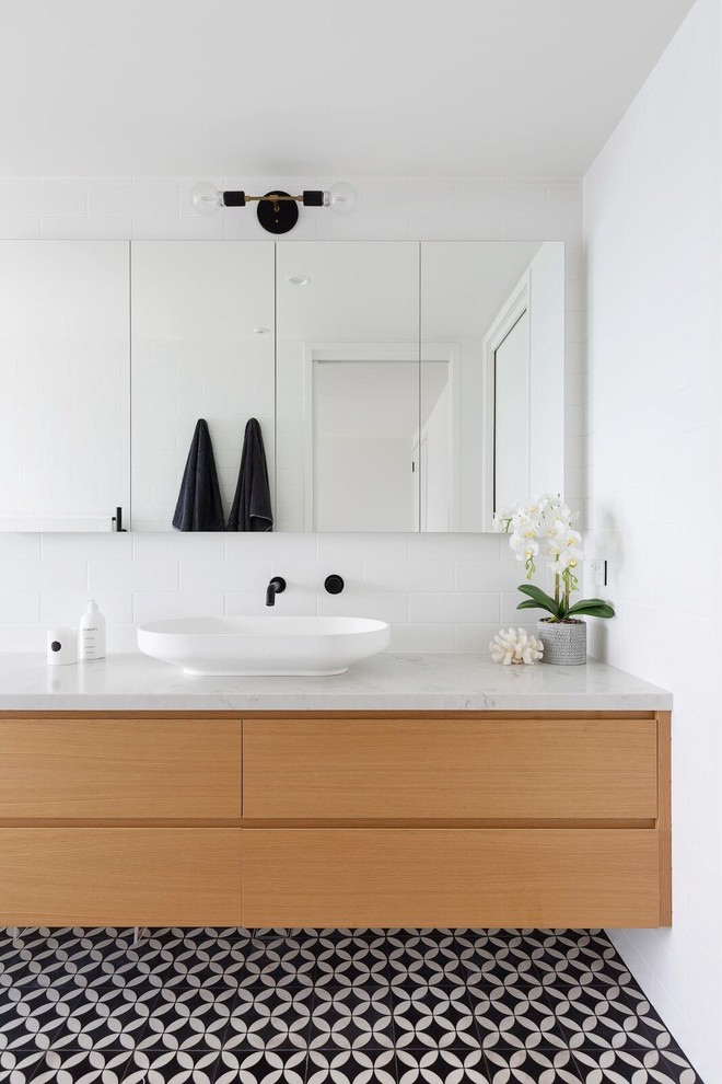 This is an example of a contemporary master bathroom in Sydney with a wall-mount toilet, white tile, subway tile, white walls, ceramic floors, marble benchtops, multi-coloured floor, flat-panel cabinets, a vessel sink, light wood cabinets and multi-coloured benchtops.