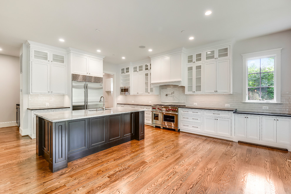 Large transitional l-shaped medium tone wood floor and brown floor open concept kitchen photo in DC Metro with an undermount sink, recessed-panel cabinets, white cabinets, quartzite countertops, white backsplash, subway tile backsplash, stainless steel appliances, an island and white countertops