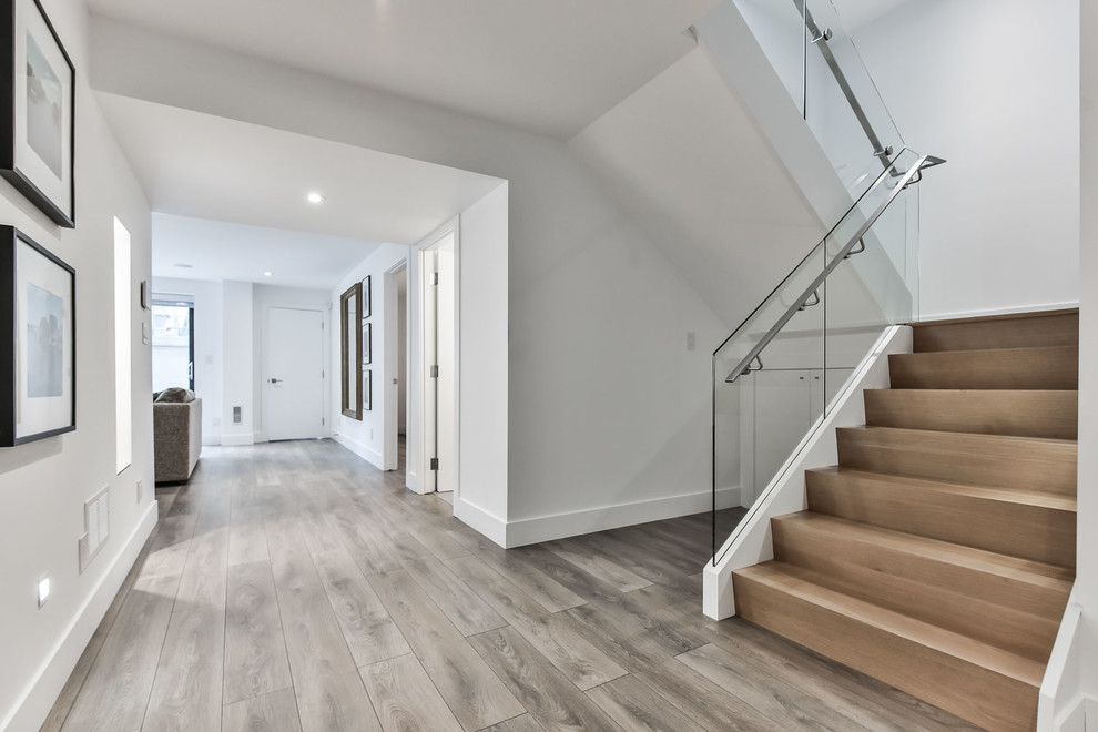 Inspiration for a mid-sized modern foyer in Toronto with white walls, ceramic floors, a single front door, a medium wood front door and grey floor.