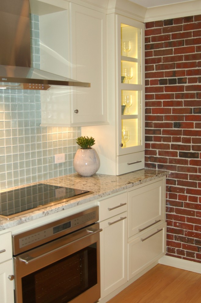 Photo of a small beach style galley kitchen in Boston with an undermount sink, recessed-panel cabinets, white cabinets, granite benchtops, stainless steel appliances, light hardwood floors and no island.