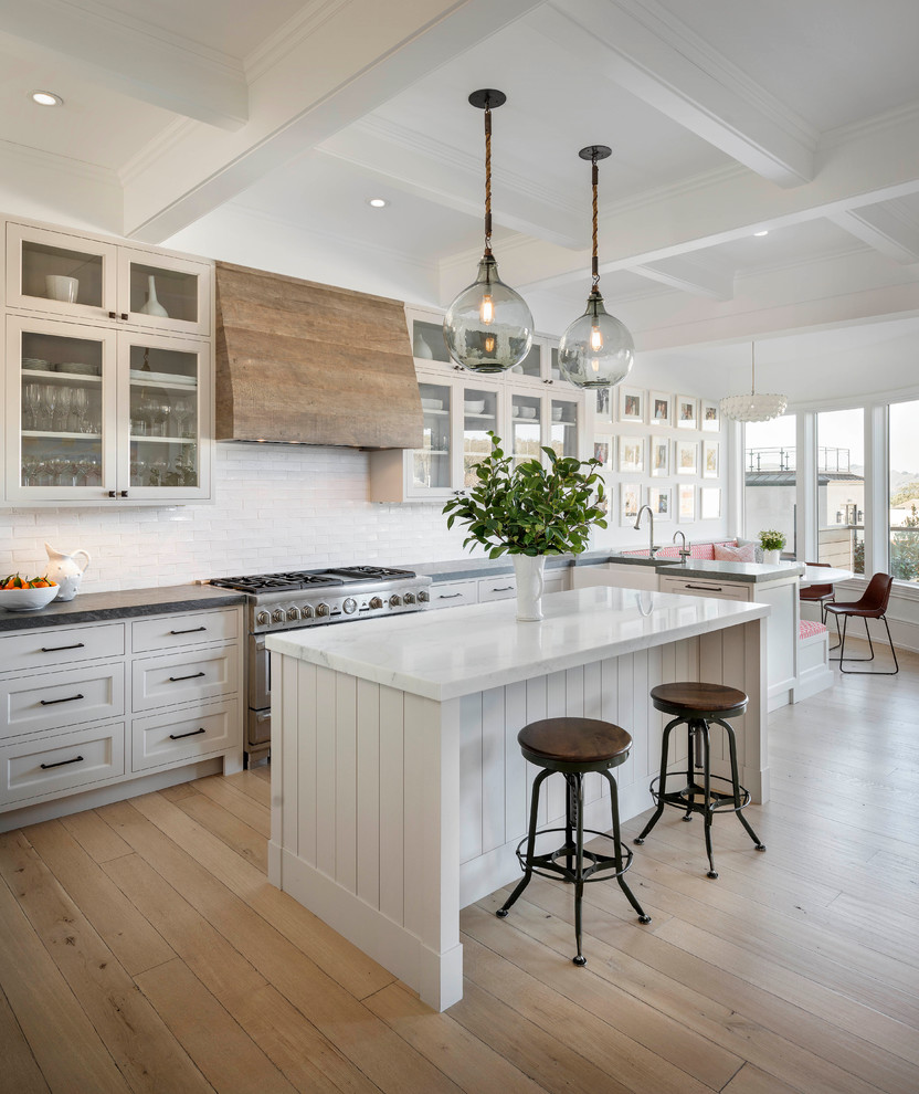 Design ideas for a transitional eat-in kitchen in San Francisco with shaker cabinets, white cabinets, white splashback, subway tile splashback, stainless steel appliances, light hardwood floors and with island.