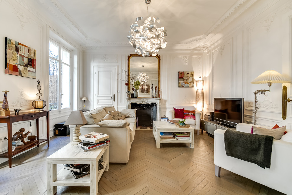 Photo of a large transitional open concept family room in Paris with white walls, a standard fireplace, a freestanding tv, painted wood floors and a stone fireplace surround.