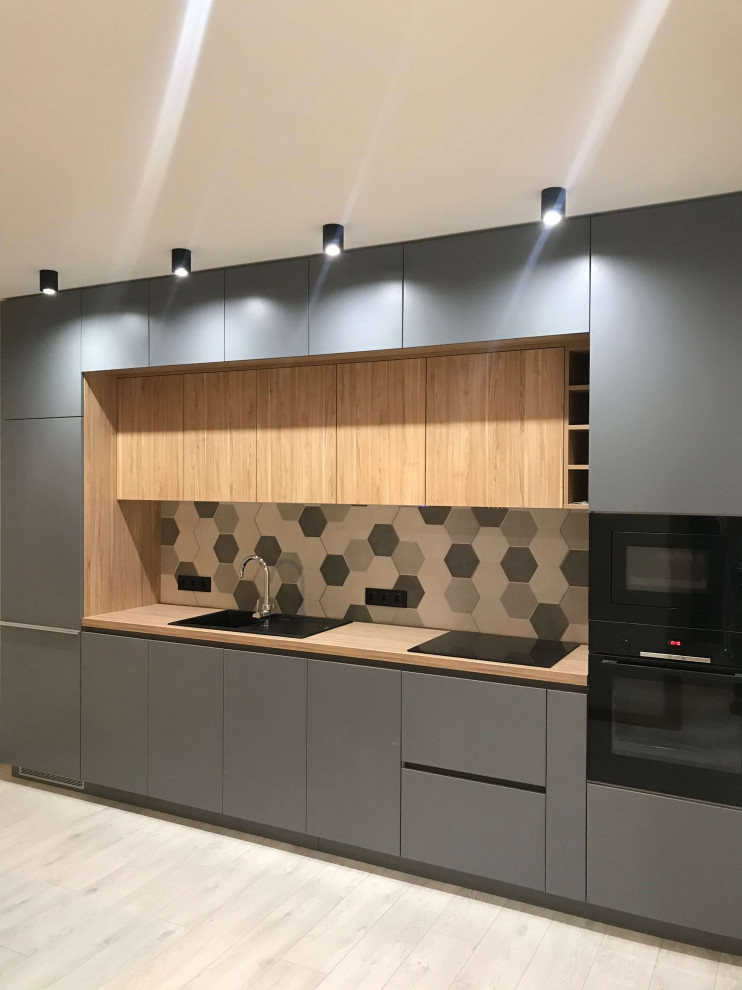This is an example of a medium sized contemporary grey and white single-wall kitchen/diner in Moscow with a single-bowl sink, flat-panel cabinets, grey cabinets, wood worktops, white splashback, ceramic splashback, integrated appliances, laminate floors, no island, beige floors and brown worktops.