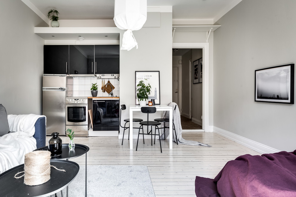 Inspiration for a small scandinavian single-wall open plan kitchen in Stockholm with flat-panel cabinets, black cabinets, wood benchtops, white splashback, light hardwood floors, no island and white floor.
